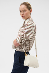 Profile view of model wearing the Oroton Eve Zip Top Crossbody in CREAM and Premium pebble leather for Women .
