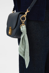 Profile view of model wearing the Oroton Eve Scarf Keyring in ROSEMARY and 100% polyester fabric for Women .