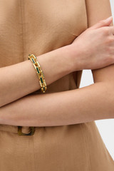 Profile view of model wearing the Oroton Emery Bracelet in HELM GREEN and Premium brass material for Women .