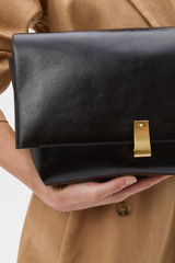 Profile view of model wearing the Oroton Etta Large Clutch in DARK CHOCOLATE and Premium crackle leather for Women .