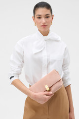 Profile view of model wearing the Oroton Etta Suede Medium Clutch in MELON and Premium suede leather for Women .