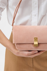 Profile view of model wearing the Oroton Etta Suede Medium Clutch in MELON and Premium suede leather for Women .