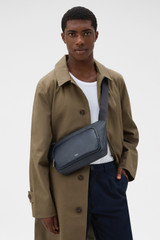 Profile view of model wearing the Oroton Larsen Sling Bag in NIGHT SKY and Premium pebble leather for Men .