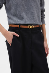 Profile view of model wearing the Oroton Olivia 20MM Logo Belt in COGNAC and Premium smooth leather for Women .