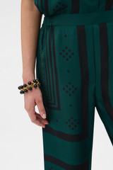 Profile view of model wearing the Oroton SPOT SCARF PRINT TROUSER in HELM GREEN and 100% silk twill fabric for Women .