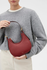 Profile view of model wearing the Oroton Dylan Mini Hobo in BERRY and Premium pebble leather for Women .