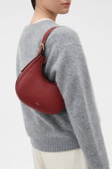 Profile view of model wearing the Oroton Dylan Mini Hobo in BERRY and Premium pebble leather for Women .