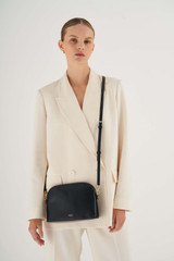 Profile view of model wearing the Oroton Inez Slim Crossbody in Black and Shiny Soft Saffiano for Women .