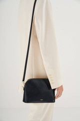 Profile view of model wearing the Oroton Inez Slim Crossbody in Black and Shiny Soft Saffiano for Women .