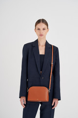 Profile view of model wearing the Oroton Inez Slim Crossbody in Cognac and Shiny Soft Saffiano for Women .