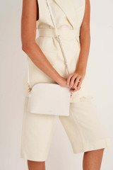 Profile view of model wearing the Oroton Inez Slim Crossbody in Cream and Saffiano Leather for Women .