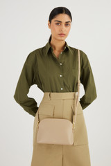 Profile view of model wearing the Oroton Inez Slim Crossbody in Fawn and Smooth Saffiano for Women .