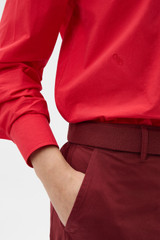 Profile view of model wearing the Oroton Wren Poplin Shirt in MARKET RED and 100% cotton fabric for Women .