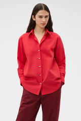 Profile view of model wearing the Oroton Wren Poplin Shirt in MARKET RED and 100% cotton fabric for Women .