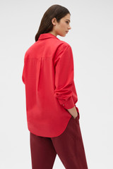 Profile view of model wearing the Oroton Wren Poplin Shirt in MARKET RED and 100% cotton fabric for Women .