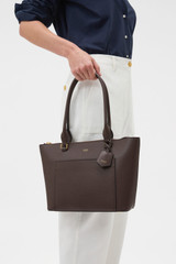 Profile view of model wearing the Oroton Iris Small Tote in Coffee Bean and Premium pebble leather for Women .