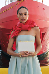Profile view of model wearing the Oroton Icon Clutch in Clotted Cream and Premium embossed leather for Women .