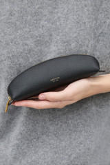 Profile view of model wearing the Oroton Eve Pencil Case in Black and Premium pebble leather for Women .