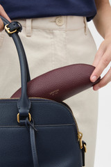 Profile view of model wearing the Oroton Eve Pencil Case in Burgundy and Premium pebble leather for Women .