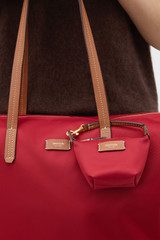 Profile view of model wearing the Oroton Lilly Nylon Pouch Charm Keyring in Dark Ruby and Nylon fabric for Women .