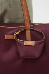 Profile view of model wearing the Oroton Lilly Nylon Pouch Charm Keyring in Burgundy and Nylon fabric for Women .