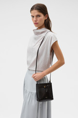 Profile view of model wearing the Oroton Margot Tiny Bucket Bag in Dark Chocolate and Premium pebble leather for Women .