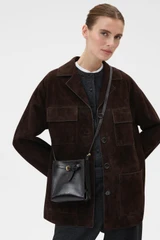Profile view of model wearing the Oroton Margot Tiny Bucket Bag in Dark Chocolate and Premium pebble leather for Women .