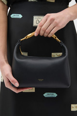Profile view of model wearing the Oroton Winnie Small Bag in Black and Premium smooth leather for Women .