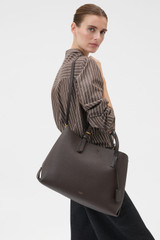 Profile view of model wearing the Oroton Margot Large Day Bag in Dark Chocolate and Premium pebble leather for Women .