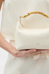 Profile view of model wearing the Oroton Winnie Eel Small Bag in Clotted Cream and Premium embossed leather for Women .
