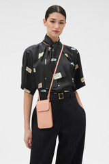 Profile view of model wearing the Oroton Margot Phone Crossbody in Melon and Premium pebble leather for Women .
