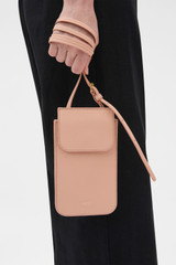 Profile view of model wearing the Oroton Margot Phone Crossbody in Melon and Premium pebble leather for Women .