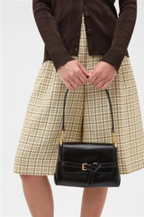 Profile view of model wearing the Oroton Margot Small Top Handle in Dark Chocolate and Premium pebble leather for Women .