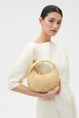 Profile view of model wearing the Oroton Clara Straw Mini Bag in Natural and Woven straw material for Women .