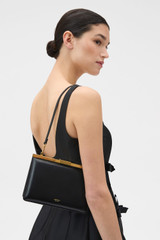 Profile view of model wearing the Oroton Icon Clutch in Black and Premium smooth leather for Women .