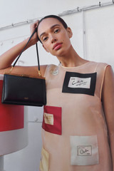 Profile view of model wearing the Oroton Icon Clutch in Black and Premium smooth leather for Women .