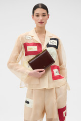 Profile view of model wearing the Oroton Icon Clutch in Copper and Premium smooth leather for Women .