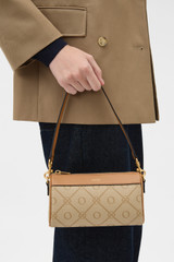 Profile view of model wearing the Oroton Harvey Signature Baguette Crossbody in Stone/Tan and Nylon canvas base cloth material with PVC coating (70% PVC, 30% polyester) for Women .