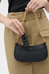 Profile view of model wearing the Oroton Harvey Signature Mini Baguette in Black and Nylon canvas base cloth material with PVC coating (70% PVC, 30% polyester) for Women .