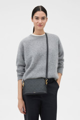 Profile view of model wearing the Oroton Harvey Signature Double Top Zip Crossbody in Black and Nylon canvas base cloth material with PVC coating (70% PVC, 30% polyester) for Women .