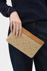 Profile view of model wearing the Oroton Harvey Signature Medium Zip Pouch in Stone/Tan and Nylon canvas base cloth material with PVC coating (70% PVC, 30% polyester) for Women .