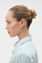 Profile view of model wearing the Oroton Jamie Huggies in Silver/Crystal and Premium brass material for Women .
