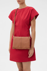 Profile view of model wearing the Oroton Dorit Small Day Bag in Cognac and Premium pebble leather  for Women .