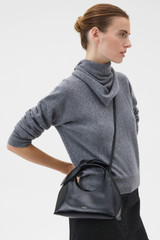 Profile view of model wearing the Oroton Myrtle Mini Bag in Black and Premium smooth leather for Women .
