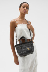 Profile view of model wearing the Oroton Calypso Small Tote in Dark Chocolate and Woven straw material for Women .