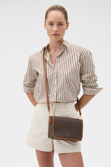 Profile view of model wearing the Oroton Laura Flap Over Crossbody in Coffee Bean/Cognac and Premium pebble leather for Women .