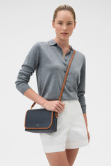 Profile view of model wearing the Oroton Laura Flap Over Crossbody in Dark Navy/Cognac and Premium pebble leather for Women .