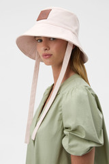 Profile view of model wearing the Oroton Nell Bucket Hat in Palest Pink and 100% cotton canvas fabric for Women .