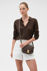 Profile view of model wearing the Oroton Yvonne Small Saddle Bag in Coffee Bean and Premium pebble leather for Women .