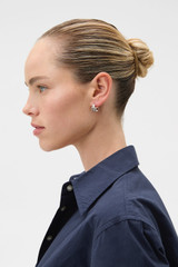 Profile view of model wearing the Oroton Rada Huggies in Silver and 12K rhodium plating for Women .